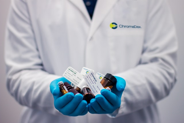 A person in a lab coat holding medication 