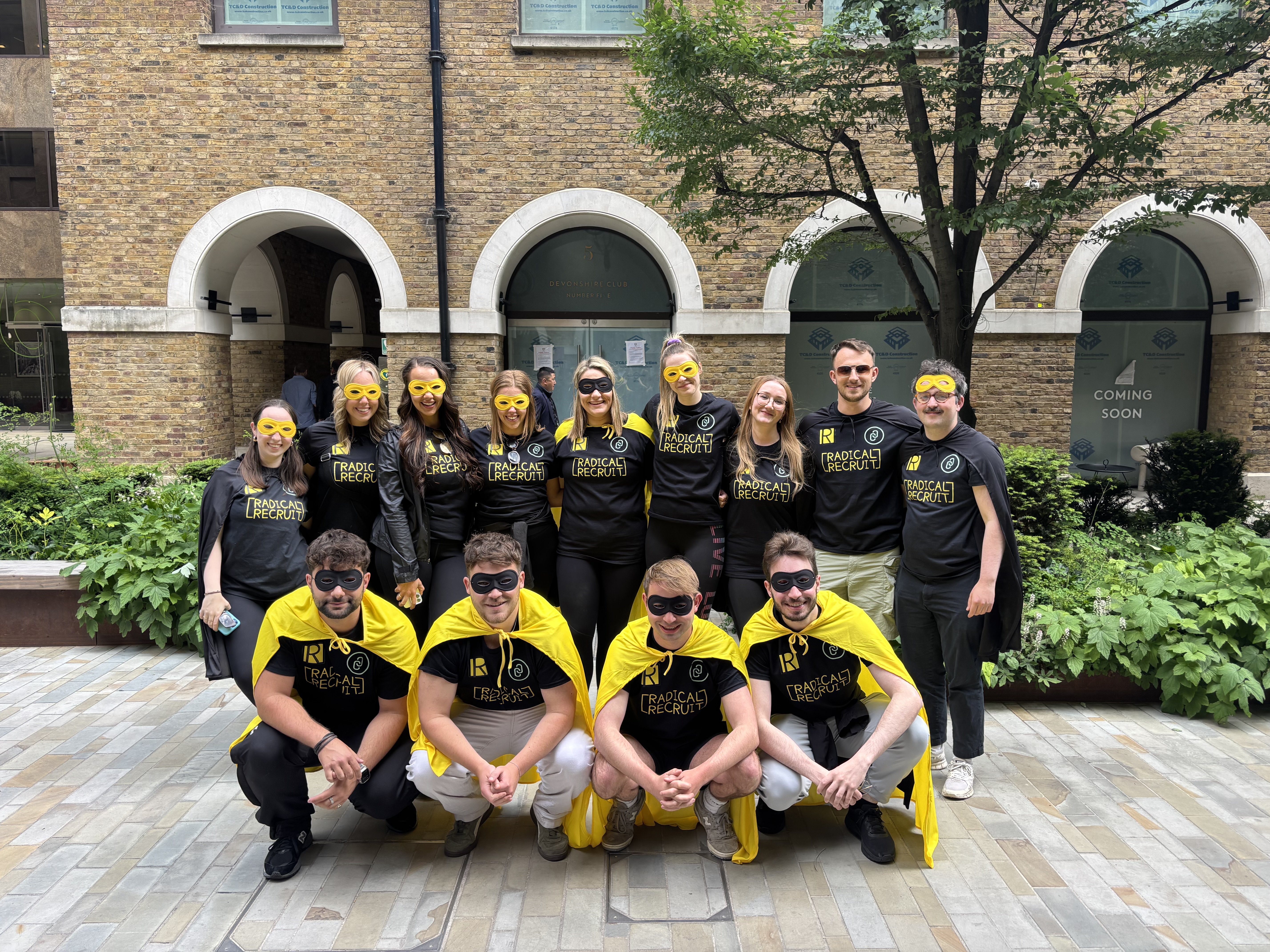 A photo of a group of people wearing matching black tops and yellow capes