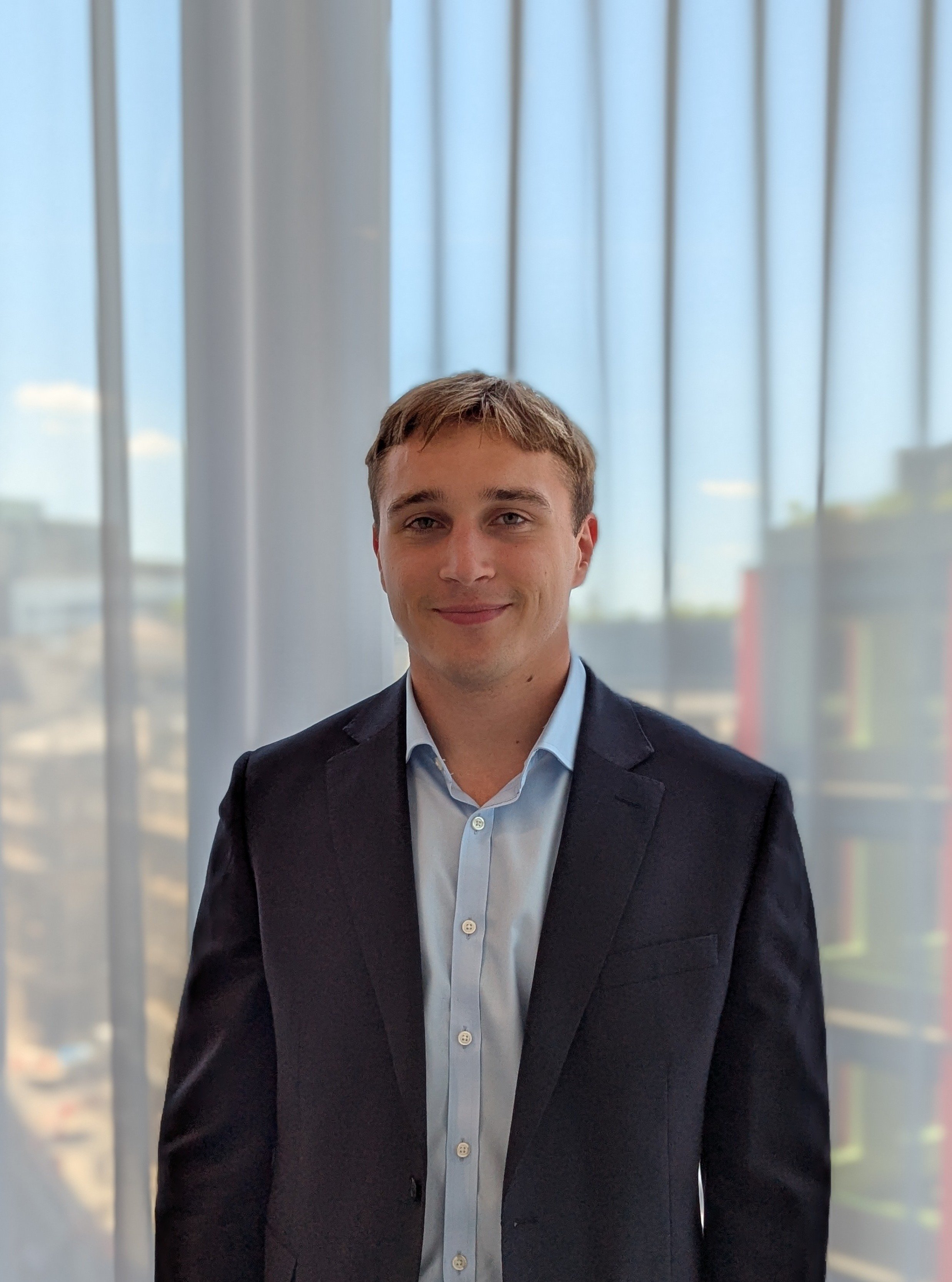 A white man with blonde hair wearing a suit in an office environment