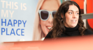 EDF employee looking into the distance, whilst standing in front of a sign that reads "this is my happy place"