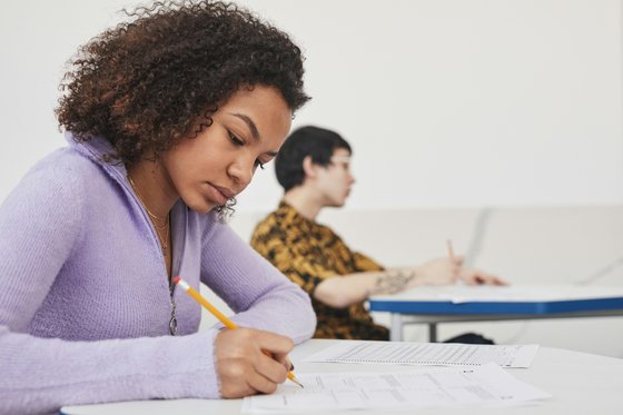 Two people in an exam hall, filling in their papers.