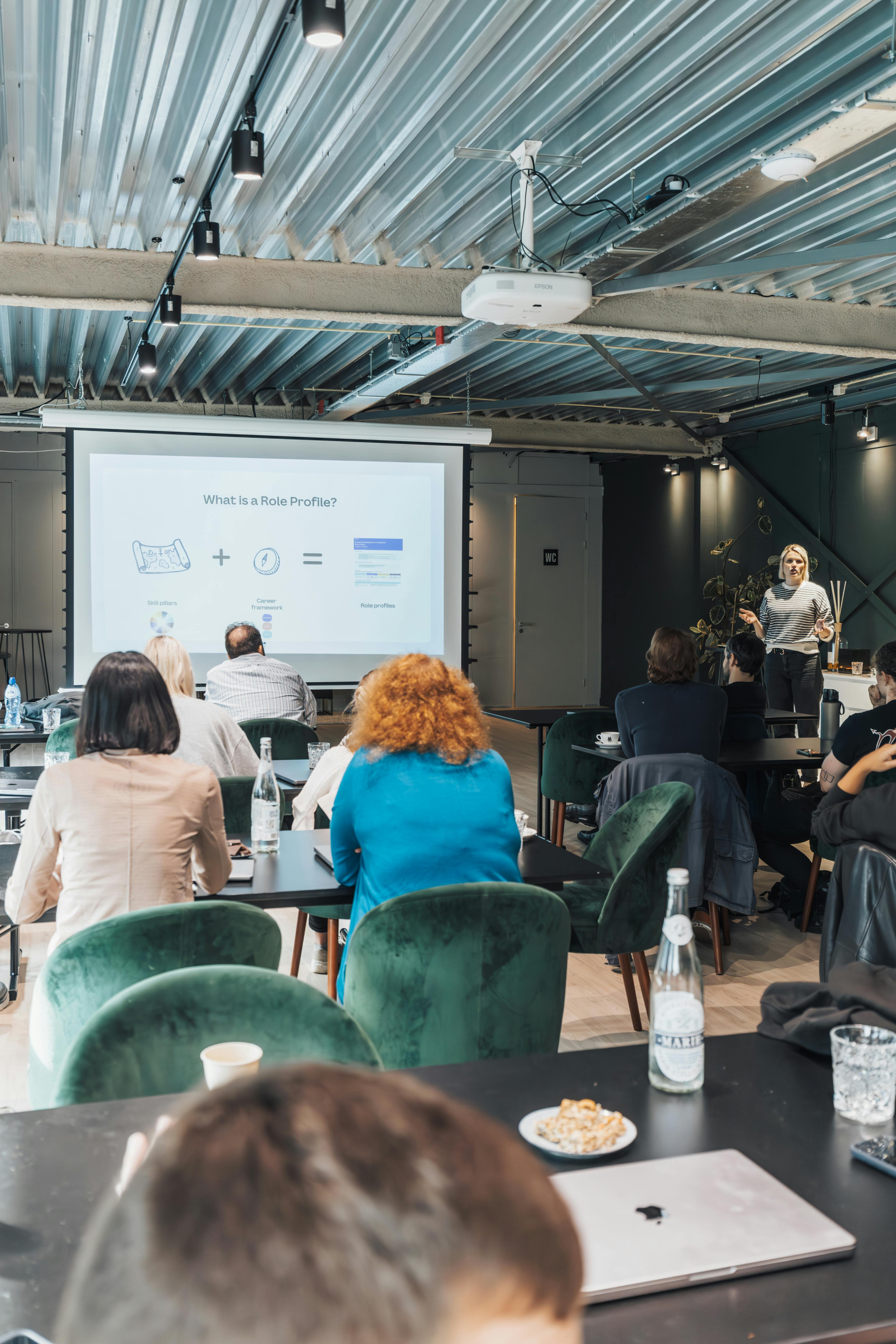 Woman giving a presentation to a room of people.