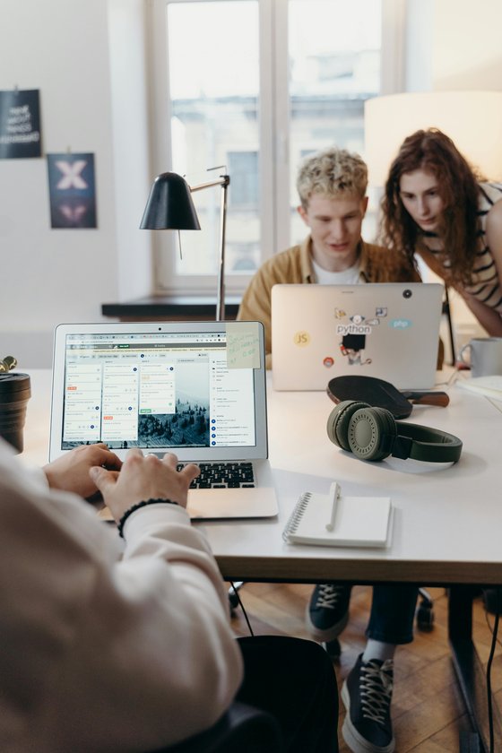 Two people leaning over a laptop in a casual office environment