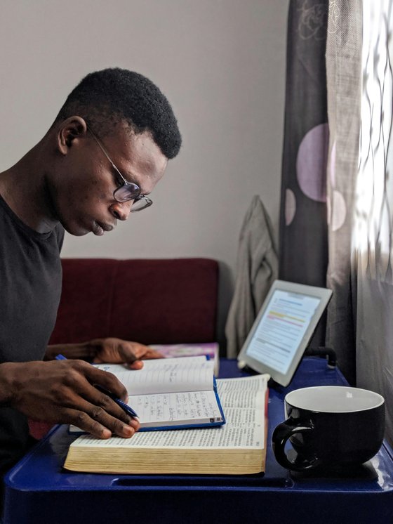 A student with books, a laptop and a mug on a desk, studying
