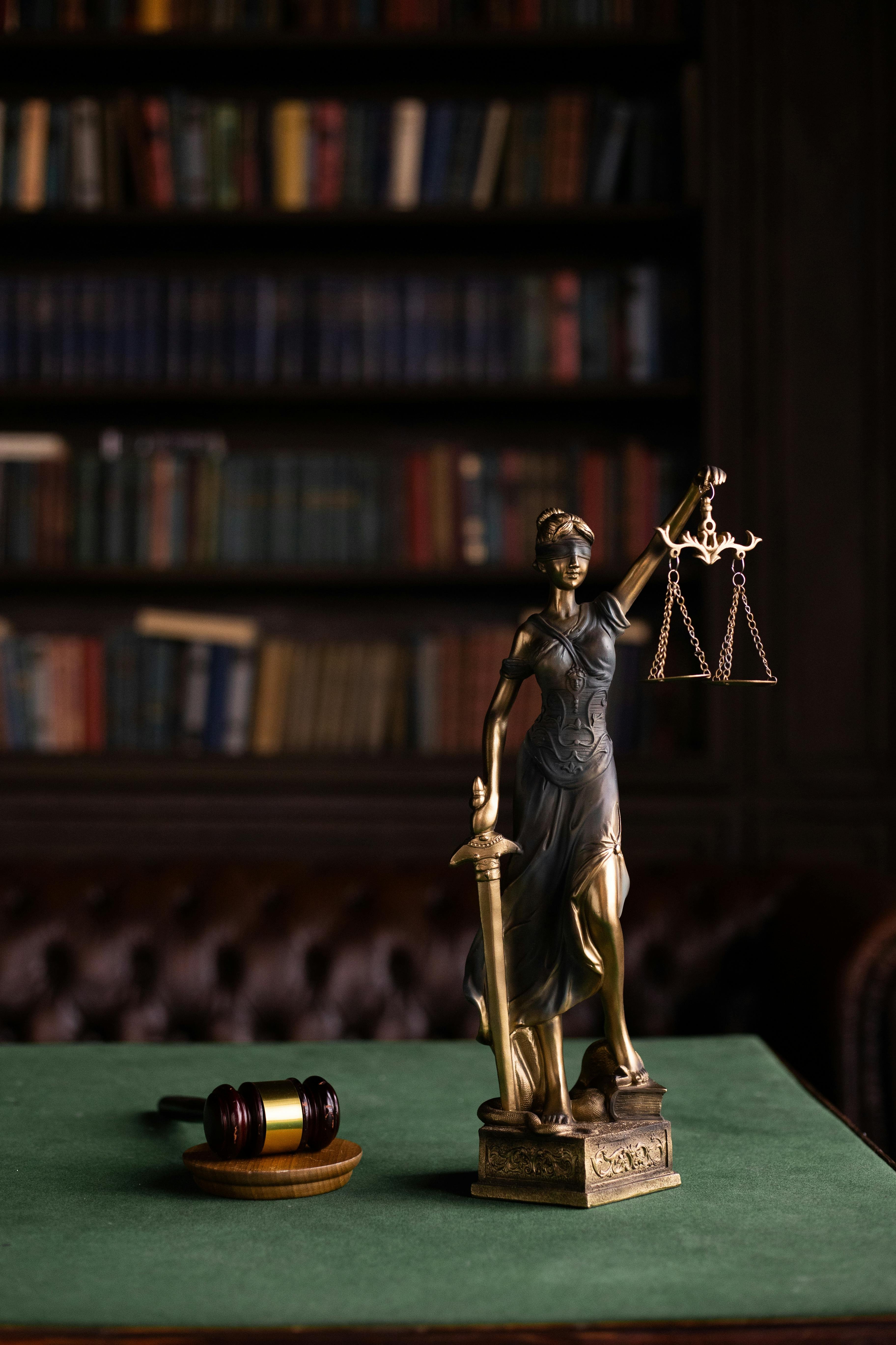 Desk in a law office with a gavel and a statue of Lady Justice on it