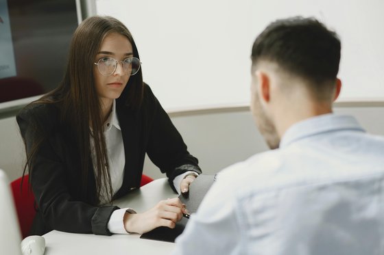 A smartly dressed woman and man sat across a table in an office environment.