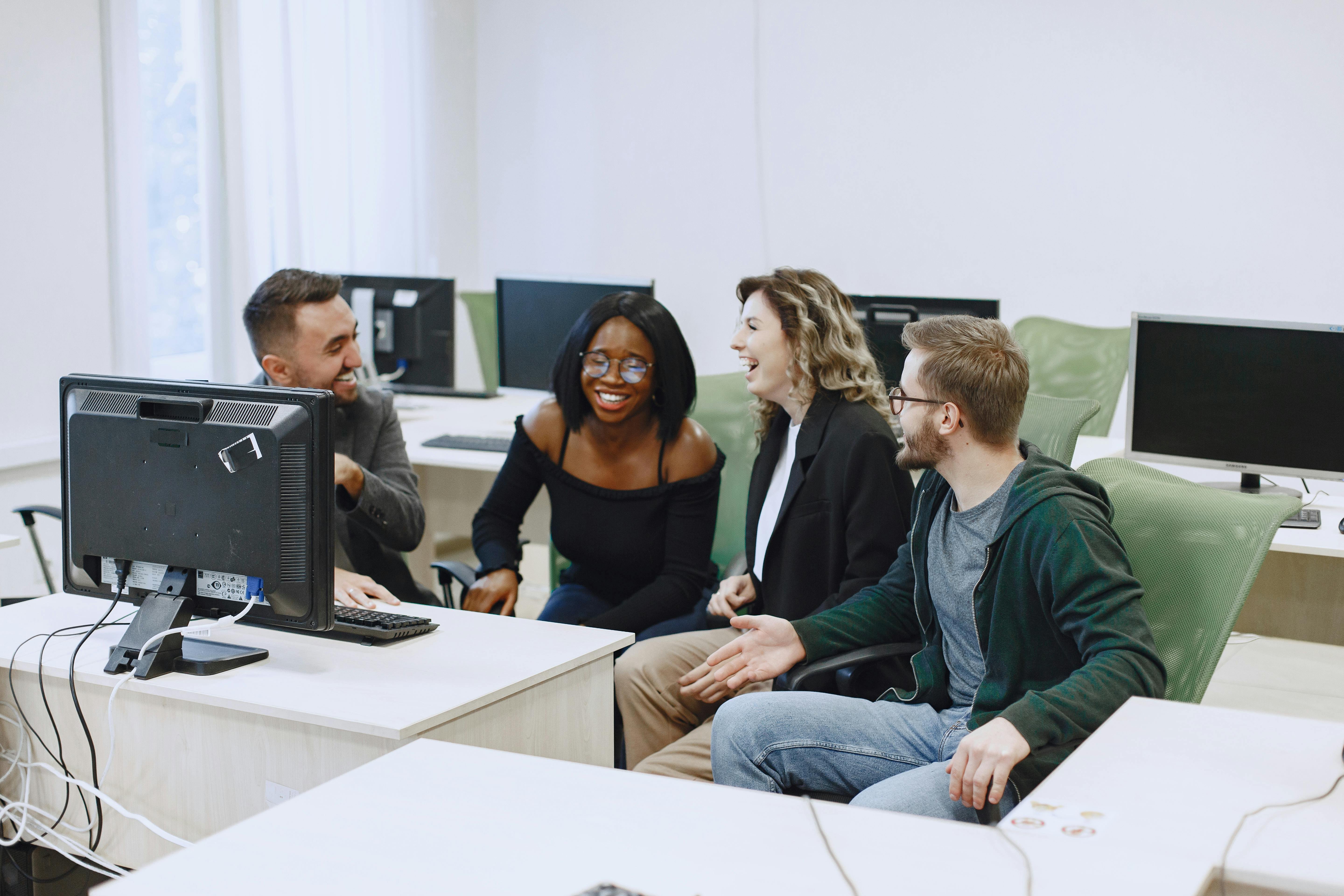 Four people in a computer lab, laughing.