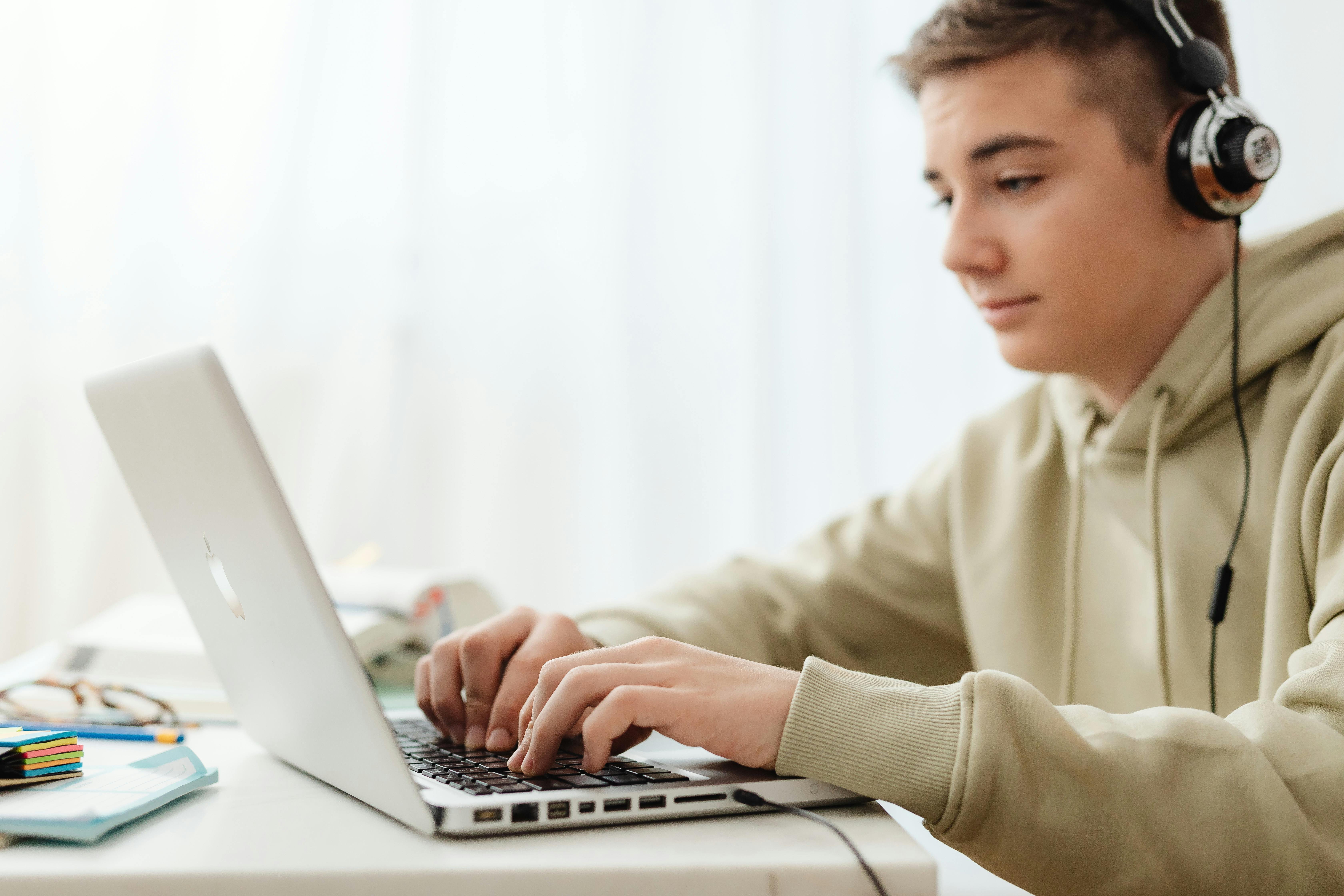 Young man using a laptop while wearing headphones.