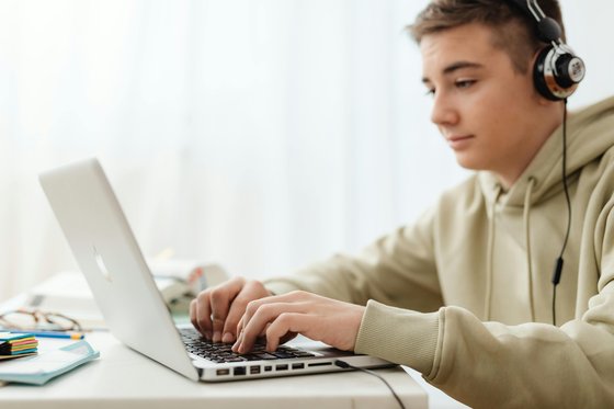 Young man using a laptop while wearing headphones.