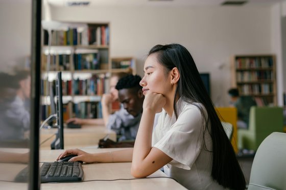 Young woman sat using a library computer.