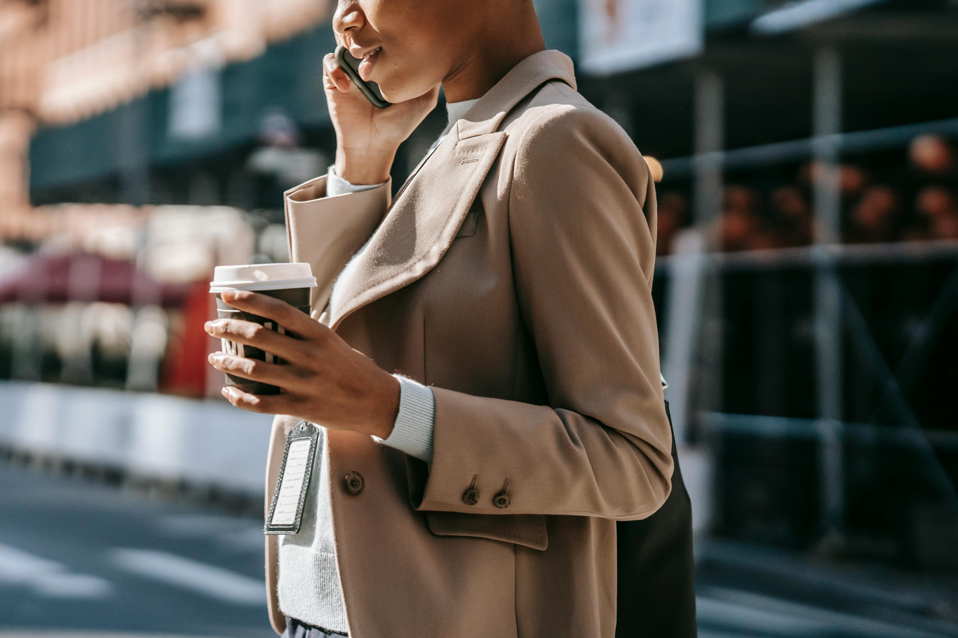 Smartly dressed woman having a conversation on her mobile phone. She is also holding a coffee cup.