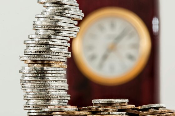 A stack of coins with a clock in the background