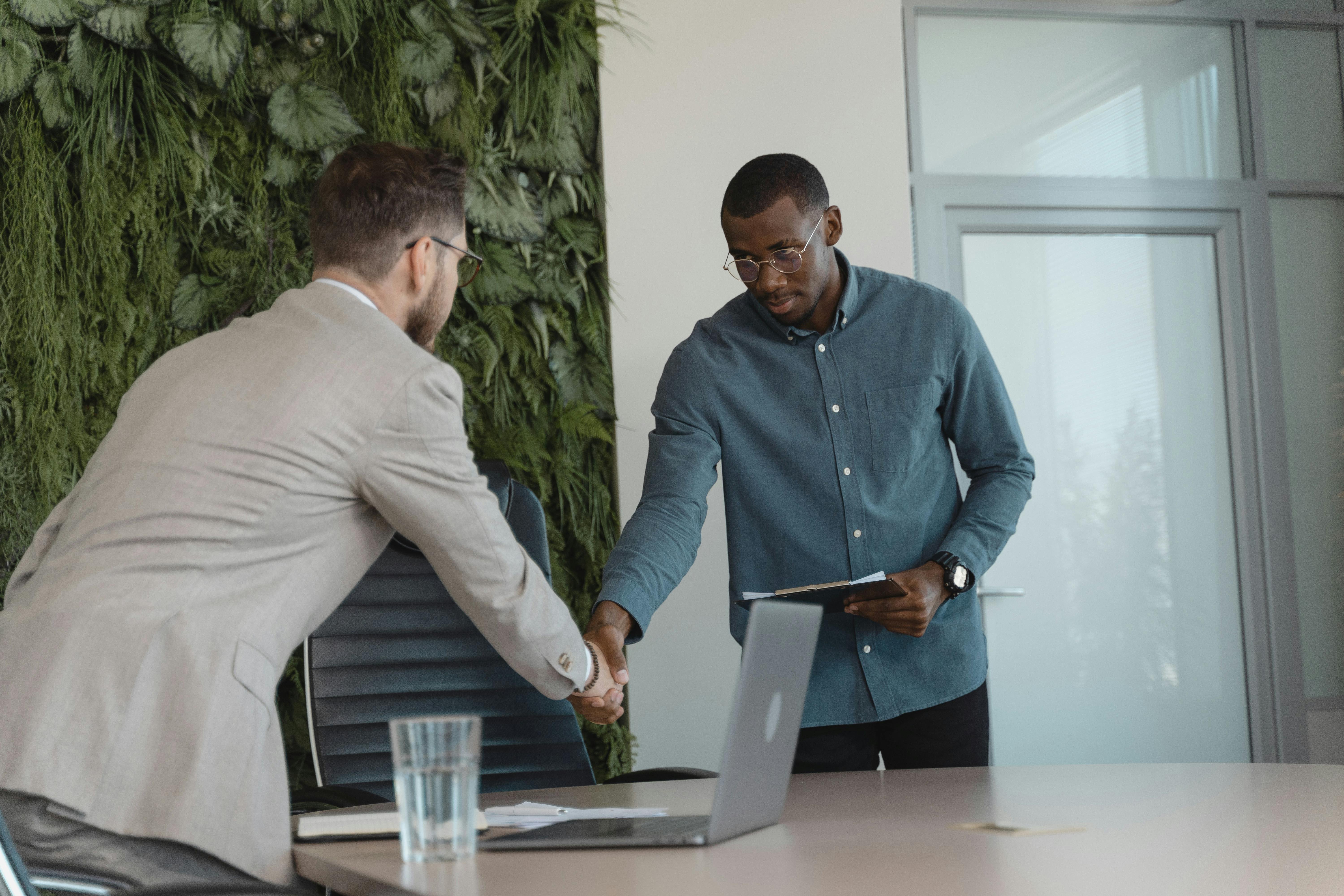 Two men shaking hands in an office environment.