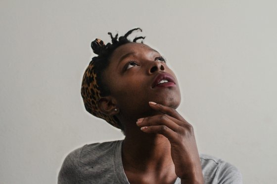 Woman looking tilting her head upwards, looking as if she is searching for answers and concentrating hard.
